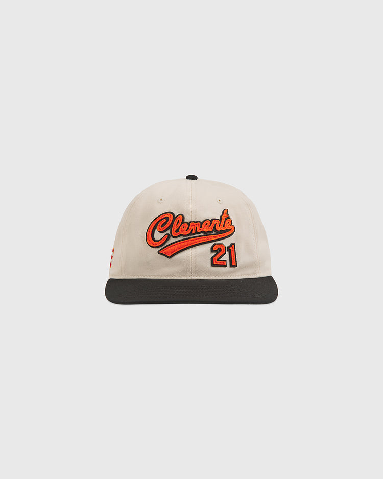 The Clemente Museum X Ebbets Field Cotton Twill Ballcap by Ebbets Field is crafted from beige cotton twill with a black brim, showcasing custom orange Clemente script and the number 21 on the front as a fitting tribute inspired by the Roberto Clemente Museum.