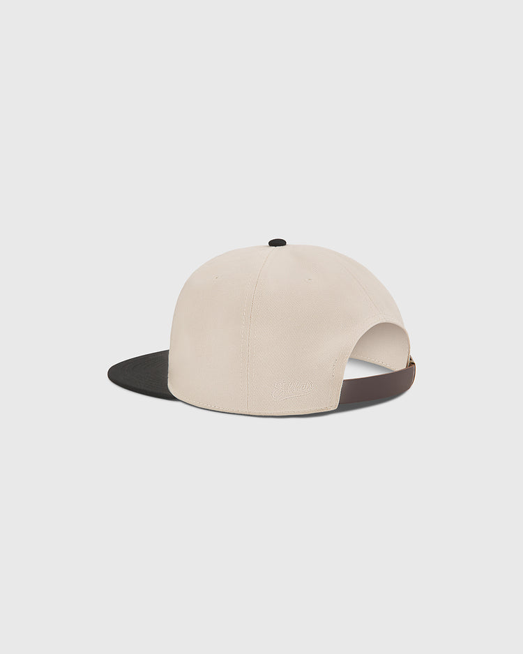 A rear view of The Clemente Museum X Ebbets Field Cotton Twill Ballcap by Ebbets Field is shown against a white background. This beige cotton twill cap features a black brim, an adjustable strap at the back, and custom Clemente script inspired by the Roberto Clemente Museum.