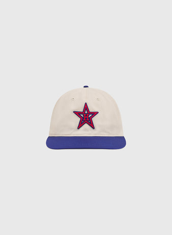 The Ebbets Field Hollywood Stars 1957 Cotton Twill Ballcap, inspired by the 1957 Hollywood Stars and reminiscent of games at Gilmore Field, features a cream-colored cotton twill crown, a blue brim, and a red and blue star emblem with the letter H on the front, displayed on a plain light background.