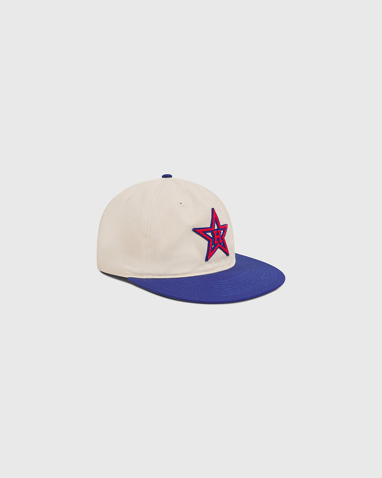 The Ebbets Field Hollywood Stars 1957 Cotton Twill Ballcap features cream cotton twill, a blue brim, and a front panel adorned with a red-outlined star patch, inspired by the 1957 Hollywood Stars of Gilmore Field, displayed against a light grey background.