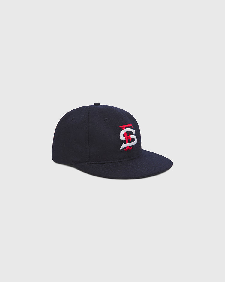 The Ebbets Field San Francisco Seals 1957 Authentic Wool Ballcap, featuring a navy blue wool construction and a red and white embroidered interlocking logo on the front, is photographed against a plain light gray background.