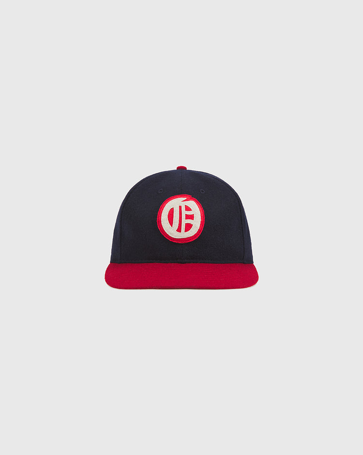 The Ebbets Field Oakland Oaks 1948 Authentic Wool Ballcap, featuring a navy blue wool body, a red brim, and a circular white-and-red embroidered logo on the front inspired by the original 1948 Oakland Oaks design, is shown against a plain light grey background.