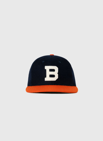 The EFF Brooklyn Bushwicks 1949 Authentic Wool Ballcap features navy blue wool, a white B on the front, and an orange brim, inspired by the original cap and shown against a plain light gray background.