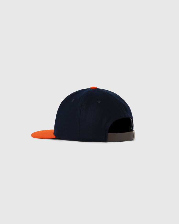 The EFF Brooklyn Bushwicks 1949 Authentic Wool Ballcap features navy blue wool, an orange brim, and a gray adjustable strap, inspired by the classic 1949 design and shown on a light gray background.