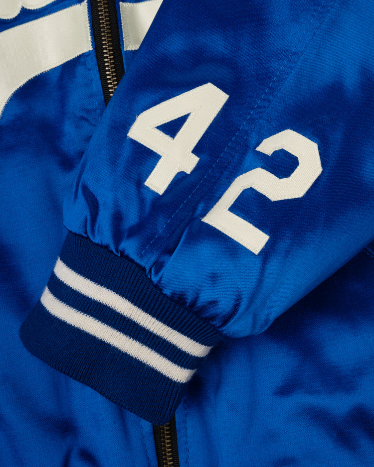 Close-up of an EFF Brooklyn Dodgers 1947-50 Authentic All Satin Varsity Jacket sleeve in royal blue with white striped cuffs, white 42 print, black zipper, and a white accent in the background.