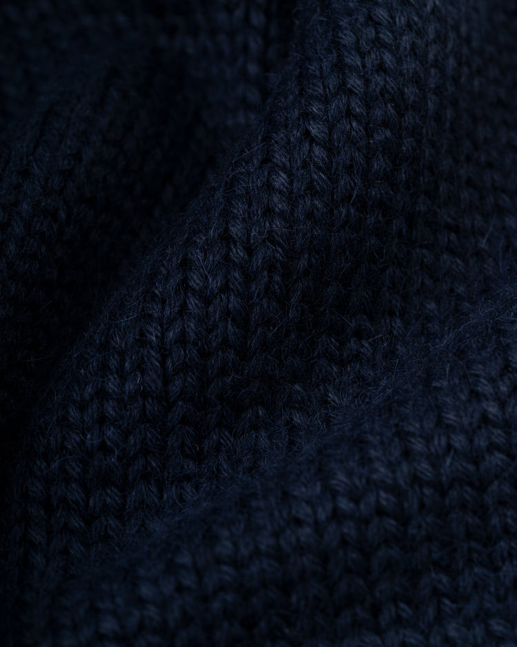 Close-up of dark blue knitted fabric from an Ebbets Field Flannels LA Angels 1961-65 Wool Shawl Collar Sweater, highlighting detailed texture, stitches, and folds with soft shadows and highlights.