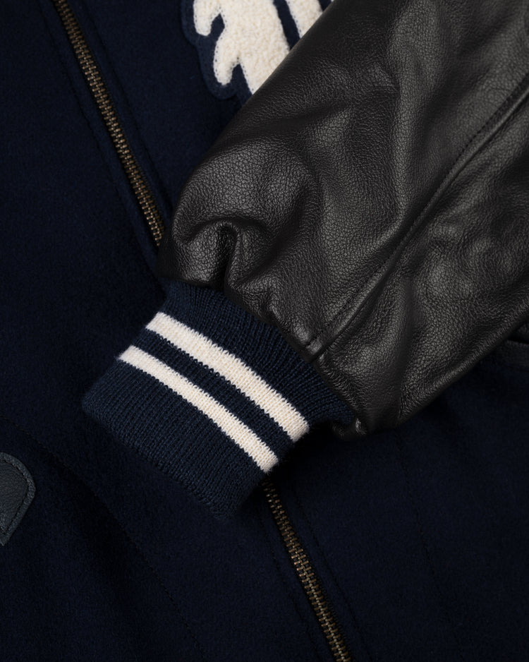 Close-up of the EFF Detroit Tigers 1955 Authentic Wool & Leather Varsity Jacket, featuring a black leather sleeve, navy and white striped ribbed cuff, and gold zipper—showcasing classic style from the era of Al Kaline.