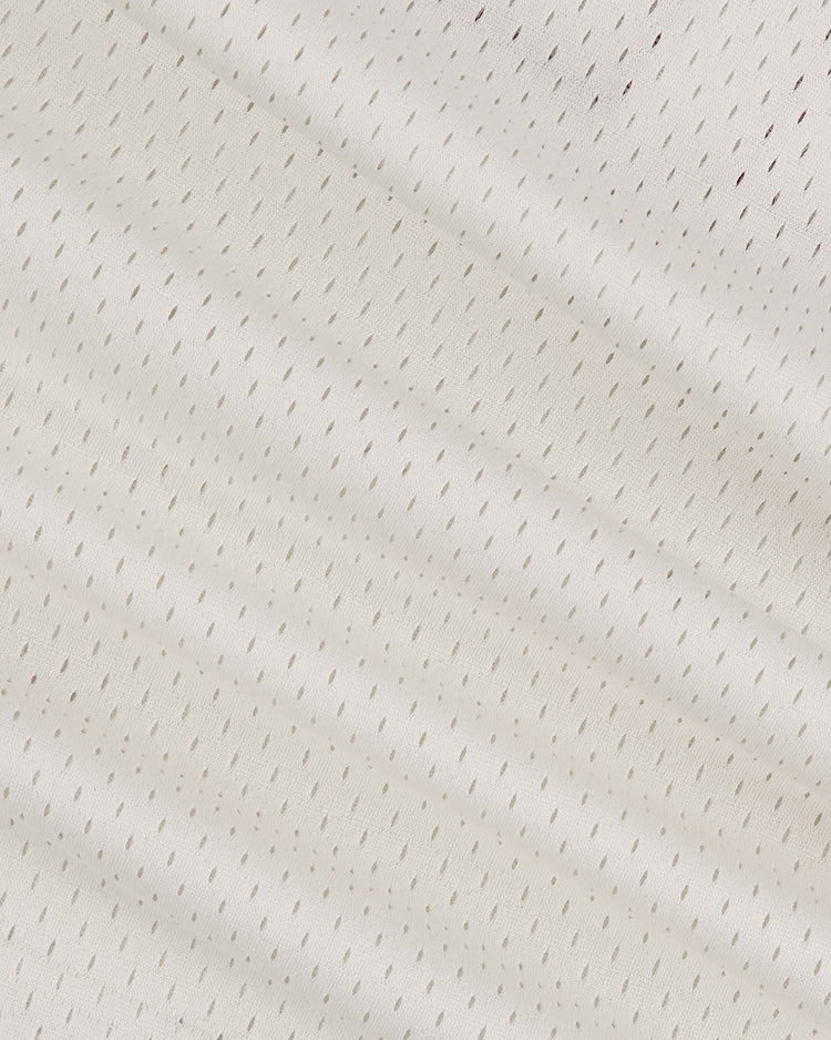 Close-up of an Ebbets Field University of Hawaii Rainbow Warriors Mesh Football Jersey, featuring white textured fabric with evenly spaced perforations and visible diagonal folds, evoking a classic athletic look.