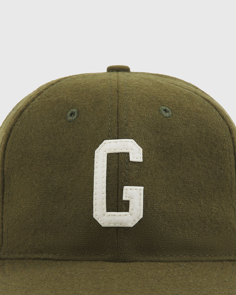 A close-up of the Ebbets Field Homestead Grays 1945 Authentic Wool Ballcap in olive green, featuring a large white letter G stitched on the front.