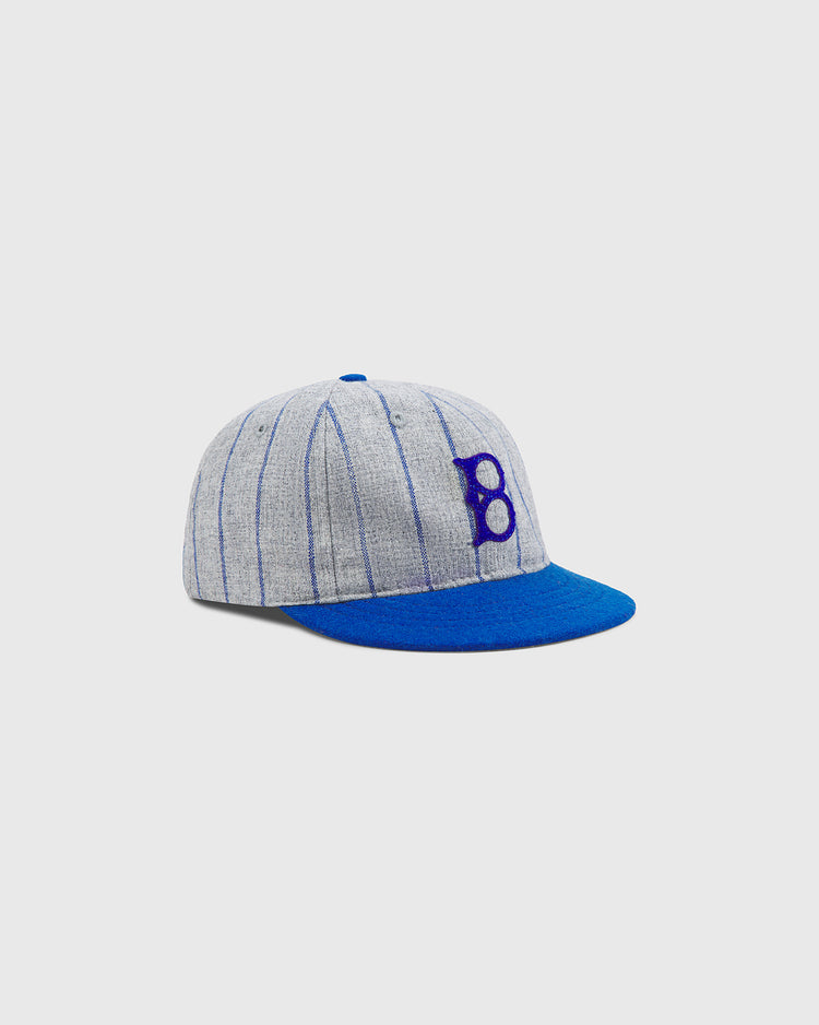 The Ebbets Field Brooklyn Royal Giants Authentic Wool Ballcap features a gray crown with blue vertical pinstripes, a blue visor, and a bold blue letter B on the front. Inspired by Black baseball history and honoring the legendary Brooklyn Royal Giants, this classic ballcap is set against a plain white background.