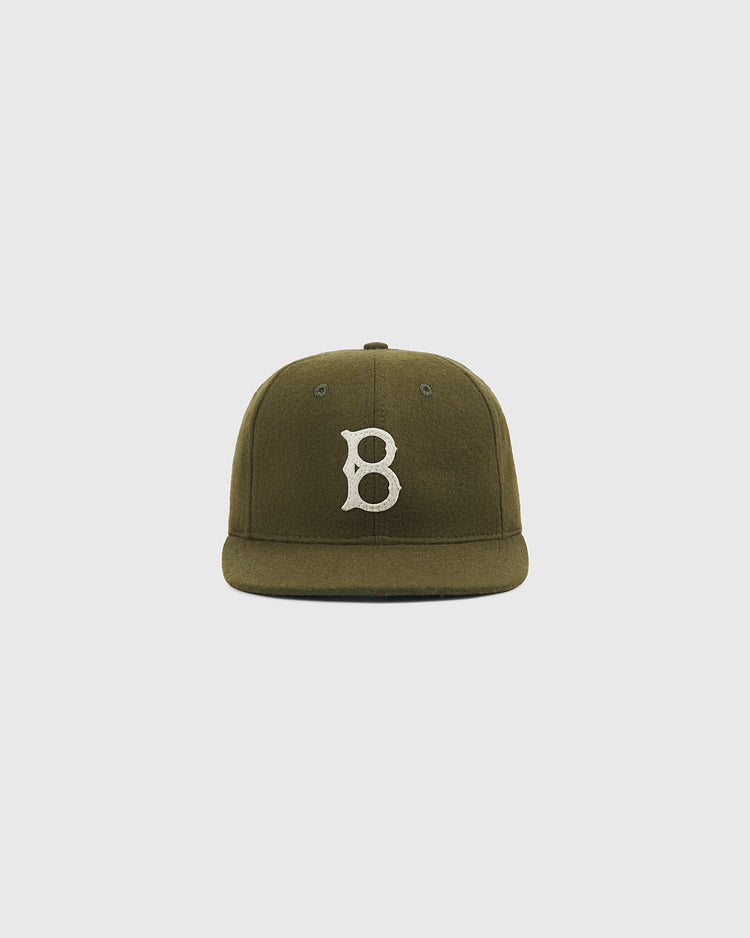 The Brooklyn Royal Giants Authentic Wool Ballcap by Ebbets Field is an olive green wool cap with a white embroidered letter B on the front, inspired by the Brooklyn Royal Giants and celebrating Black baseball history, shown against a plain light gray background.
