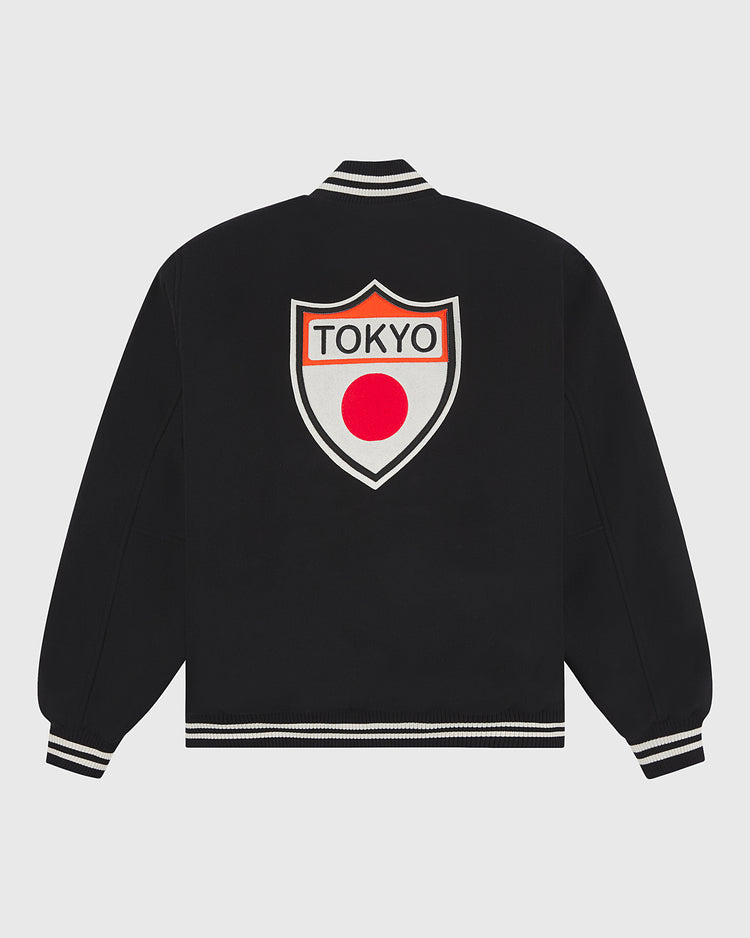 Ebbets Field’s Tokyo Giants All-Wool Varsity Jacket features a black all-wool construction with white and black striped cuffs and collar, and is distinguished by a large shield-shaped patch on the back reading “TOKYO” above a red dot—an homage to Japanese professional baseball and the legendary Tokyo Giants.