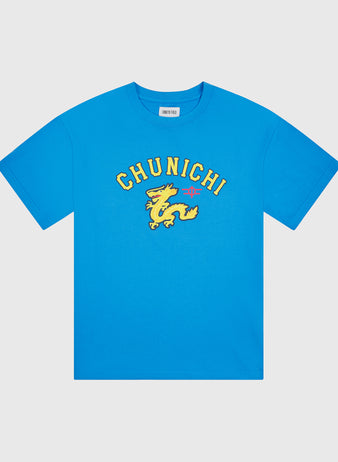 The Chunichi Dragons Short Sleeve Graphic T-Shirt by Ebbets Field features a blue pigment-dyed design with “CHUNICHI” in bold yellow letters above a yellow dragon graphic and a small pink star on the chest, taking inspiration from vintage Japanese baseball shirts. The t-shirt is shown against a plain white background.