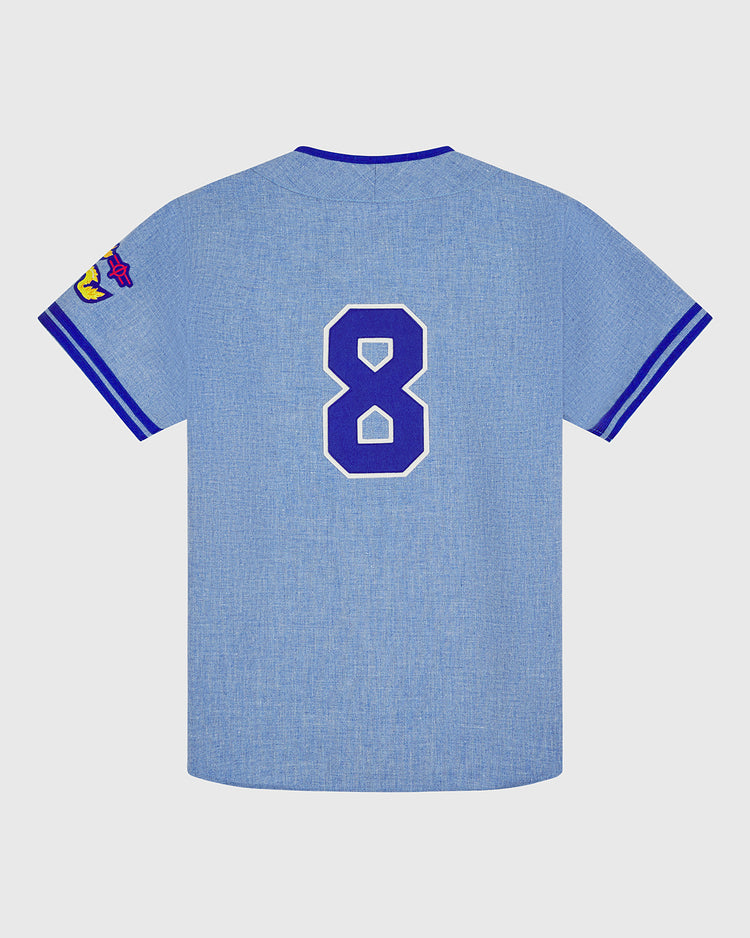 The Ebbets Field Chunichi Dragons 1969 Authentic Wool Road Jersey is a light blue road jersey inspired by the 1969 team, featuring blue and white striped sleeves, a bold white-outlined number 8 on the back, and a vibrant patch on the left sleeve that nods to classic baseball flannel designs.