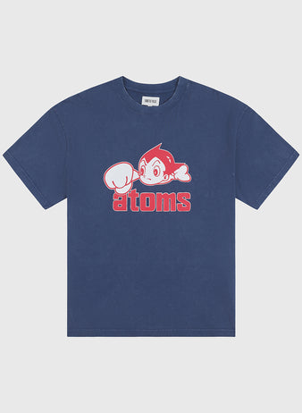 The Ebbets Field Sankei Atoms Pigment-Dyed Short Sleeve Graphic T-Shirt features a cartoon character with a raised fist above bold red “atoms” lettering, channeling vintage Tokyo baseball style and playful retro flair.