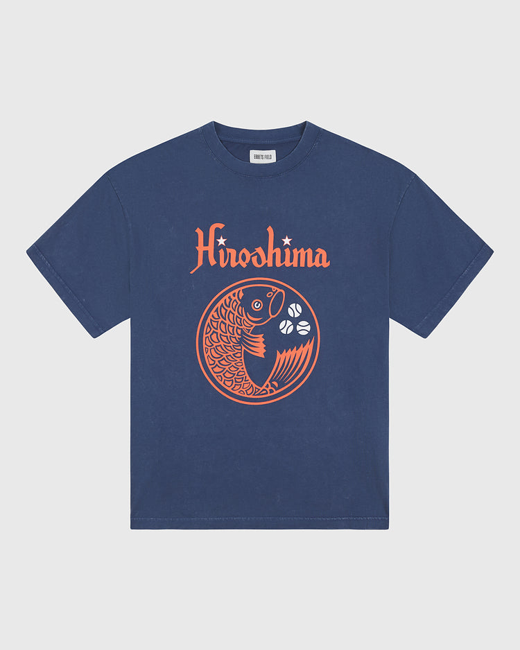 This Ebbets Field Hiroshima Carp Pigment-Dyed Short Sleeve Graphic T-Shirt is a vintage-inspired cotton tee in navy blue, showcasing bold orange “Hiroshima” text above a striking, stylized koi fish and three white flowers arranged in a circular design on the front—a fresh take on classic Hiroshima Carp t-shirt style.