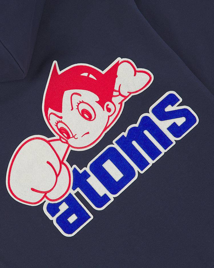 A graphic of a red-haired cartoon character with a raised fist sits above the bold blue word “atoms” on dark heavyweight cotton terry—capturing vintage charm on the Ebbets Field Sankei Atoms Full-Zip Hoodie.