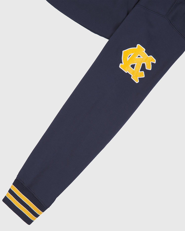 The Kansas City Monarchs 1924 Road Jersey Pullover Hoodie by Ebbets Field features a navy sleeve with yellow and white stripe cuff and a yellow-white NC patch near the elbow on a plain background.