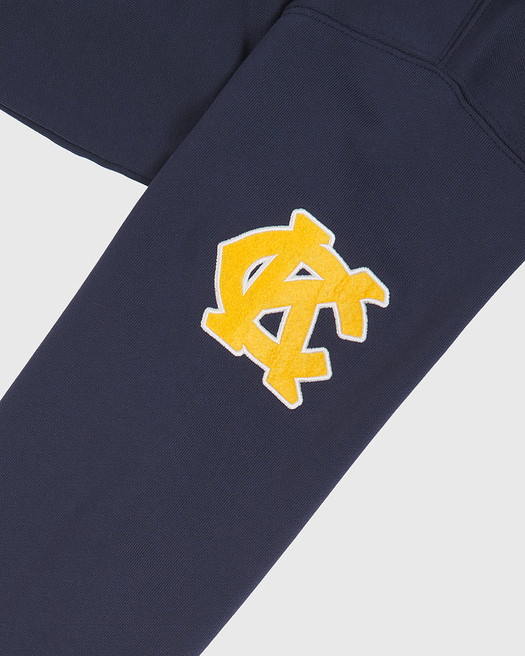 Navy blue Kansas City Monarchs 1924 Road Jersey Pullover Hoodie by Ebbets Field with a yellow and white varsity-style interlocking NC logo patch sewn on.