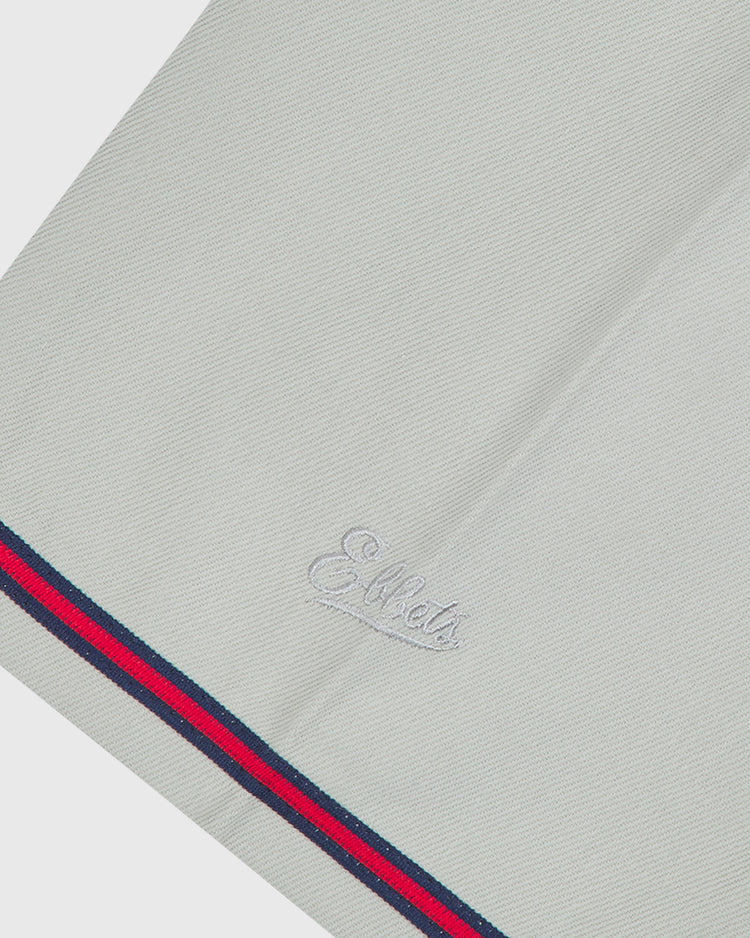 Close-up of a light gray Kansas City Monarchs 1936 Road Jersey Cotton Twill with a script logo embroidered near the hem, which is trimmed with navy and red stripes.