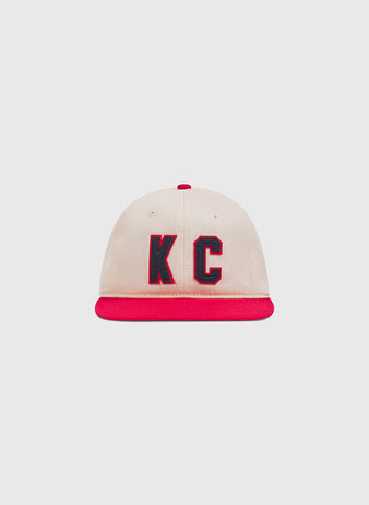 Ebbets Field Kansas City Monarchs 1942 Cotton Twill Ballcap in cream with a red brim, red top button, and navy blue KC lettering on the front.