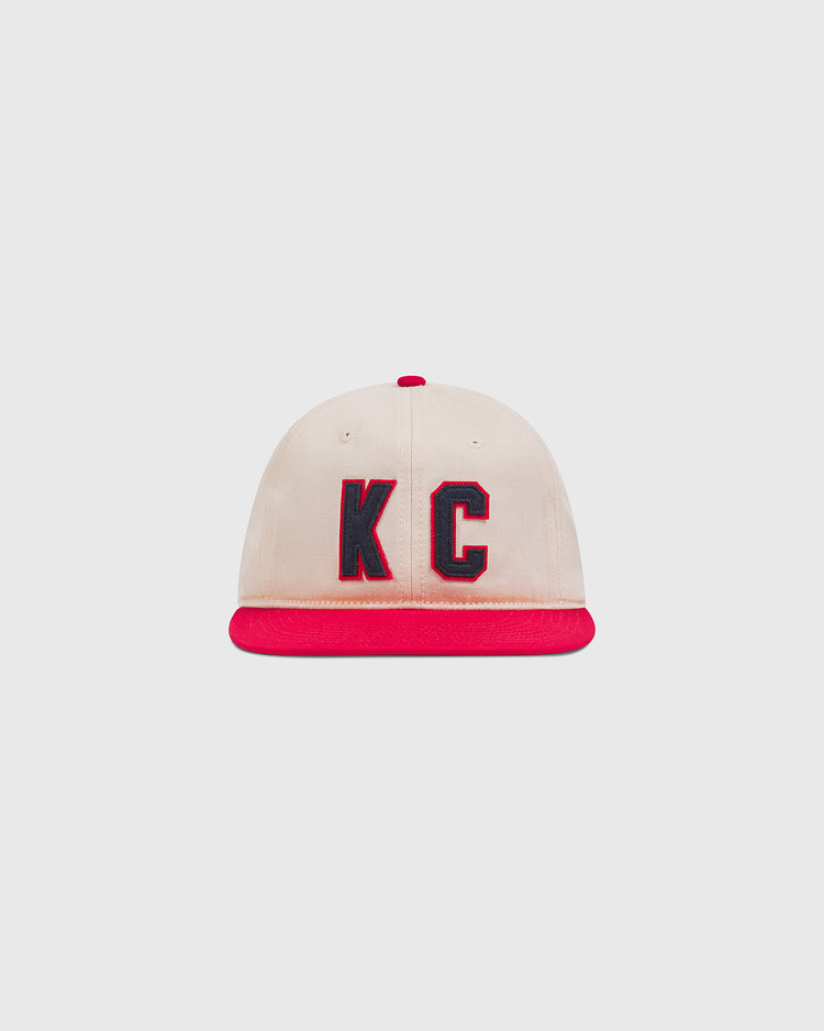 Ebbets Field Kansas City Monarchs 1942 Cotton Twill Ballcap in cream with a red brim, red top button, and navy blue KC lettering on the front.
