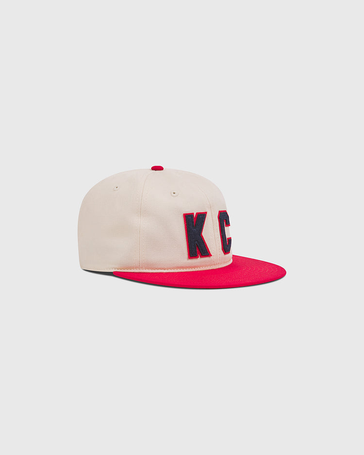Ebbets Field Kansas City Monarchs 1942 Cotton Twill Ballcap in cream with a red brim, red top button, and navy blue KC letters with a red outline on the front.