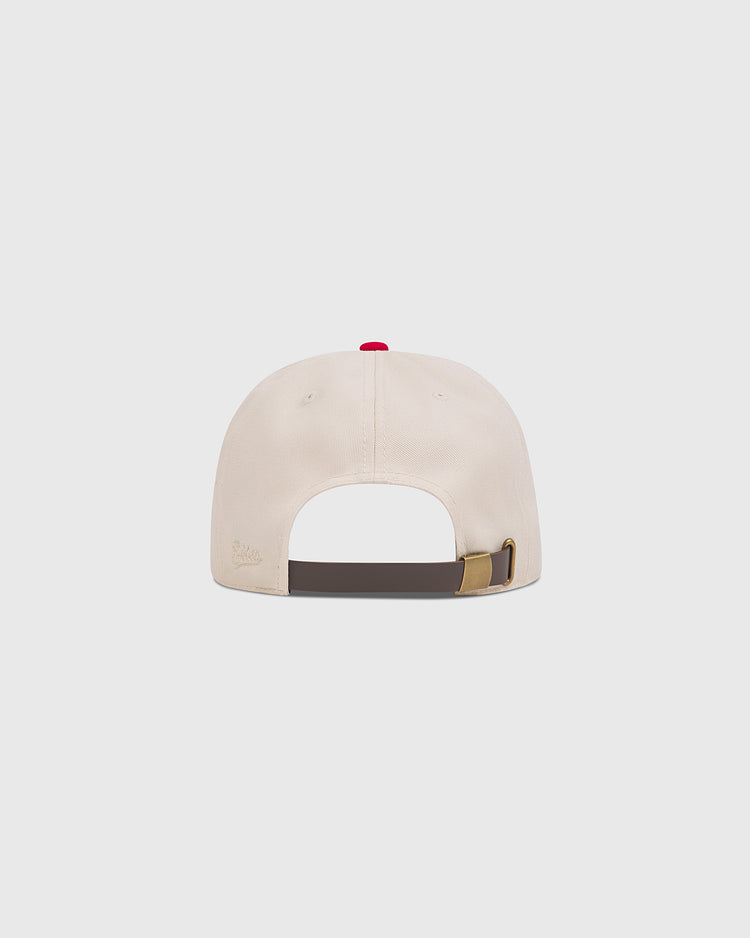 Back view of a cream Ebbets Field Kansas City Monarchs 1942 Cotton Twill Ballcap with a red top button and an adjustable brown leather strap with a brass buckle.