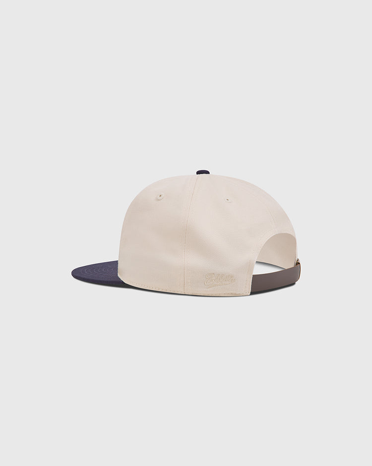 Rear view of an Atlanta Black Crackers 1940 Cotton Twill Ballcap in cream cotton twill with a dark blue brim and a leather adjustable strap at the back.
