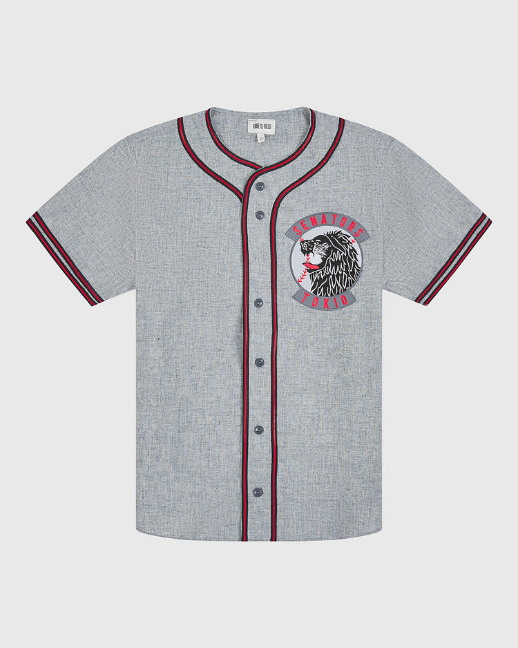 Channel classic baseball style with the Ebbets Field Tokio Senators 1936 Authentic Wool Road Jersey. This vintage gray wool jersey features black buttons, maroon and black striped detailing on the cuffs and collar, and a chest patch showcasing a stylized Native American chief alongside red “Senators World” lettering. Inspired by the original 1936 road uniforms of the Tokio Senators, this piece captures timeless baseball heritage.