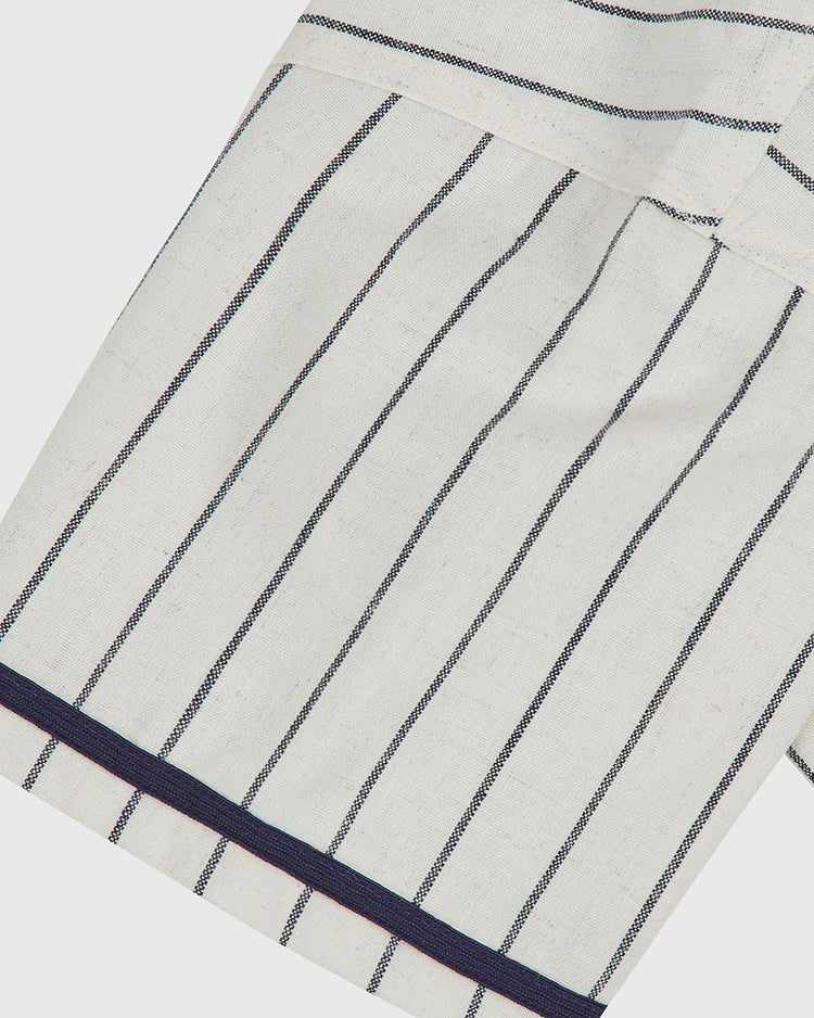 Close-up of the cream-colored Atlanta Black Crackers 1940 Authentic Home Jersey by Ebbets Field, featuring vertical navy blue stripes and a horizontal navy stripe near the hem, possibly part of a sleeve or shirt.