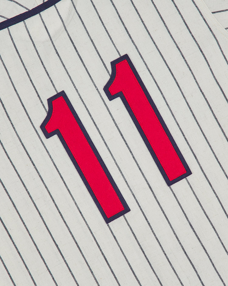A red number 11 outlined in navy blue is displayed on an Atlanta Black Crackers 1940 Authentic Home Jersey by Ebbets Field, featuring classic white pinstripes and shown at an angle.