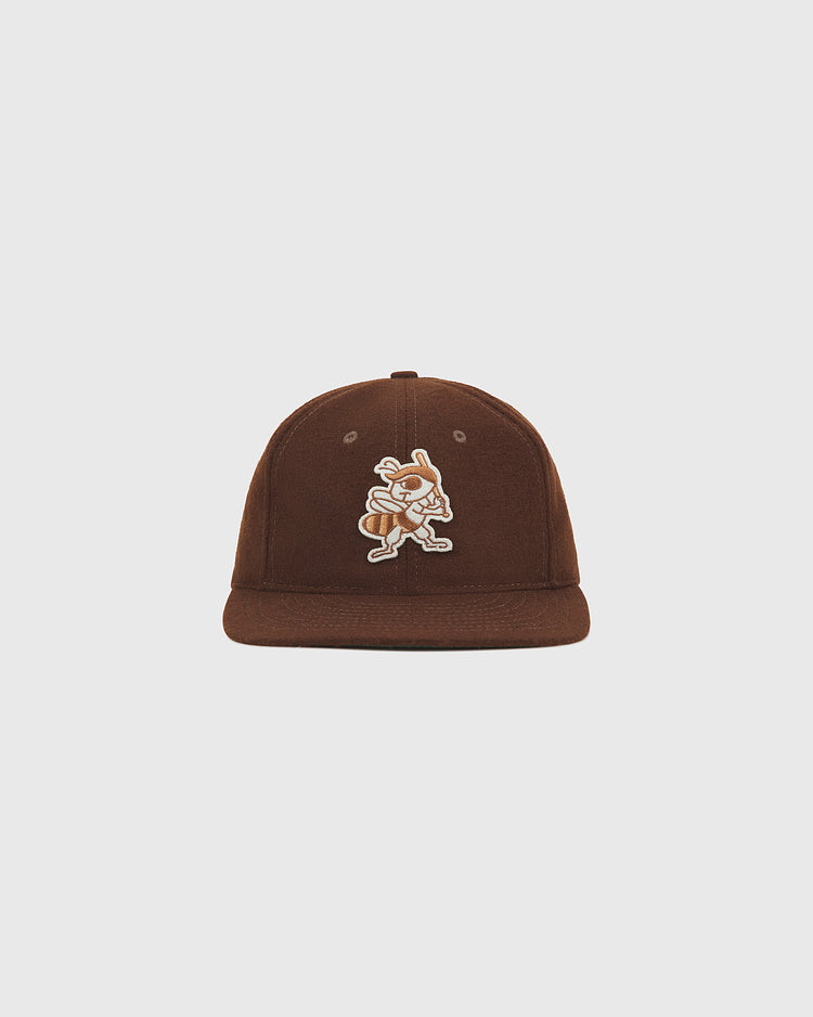 The Ebbets Field Salt Lake City Bees 1959 Wool Ballcap is shown against a plain white background, featuring a brown color and a cartoon bee mascot patch on the front, inspired by the 1959 Salt Lake City Bees of the Pacific Coast League.