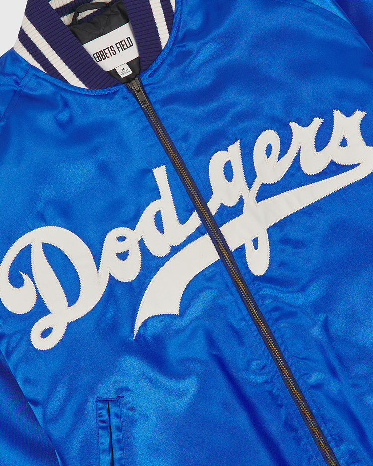 Close-up of a vivid blue satin Brooklyn Dodgers 1947-50 Authentic All Satin Varsity Jacket by EFF, featuring “Dodgers” in white script across the front and a ribbed collar. A small EFF tag is visible at the neckline, evoking the iconic team jacket famously worn by Jackie Robinson.