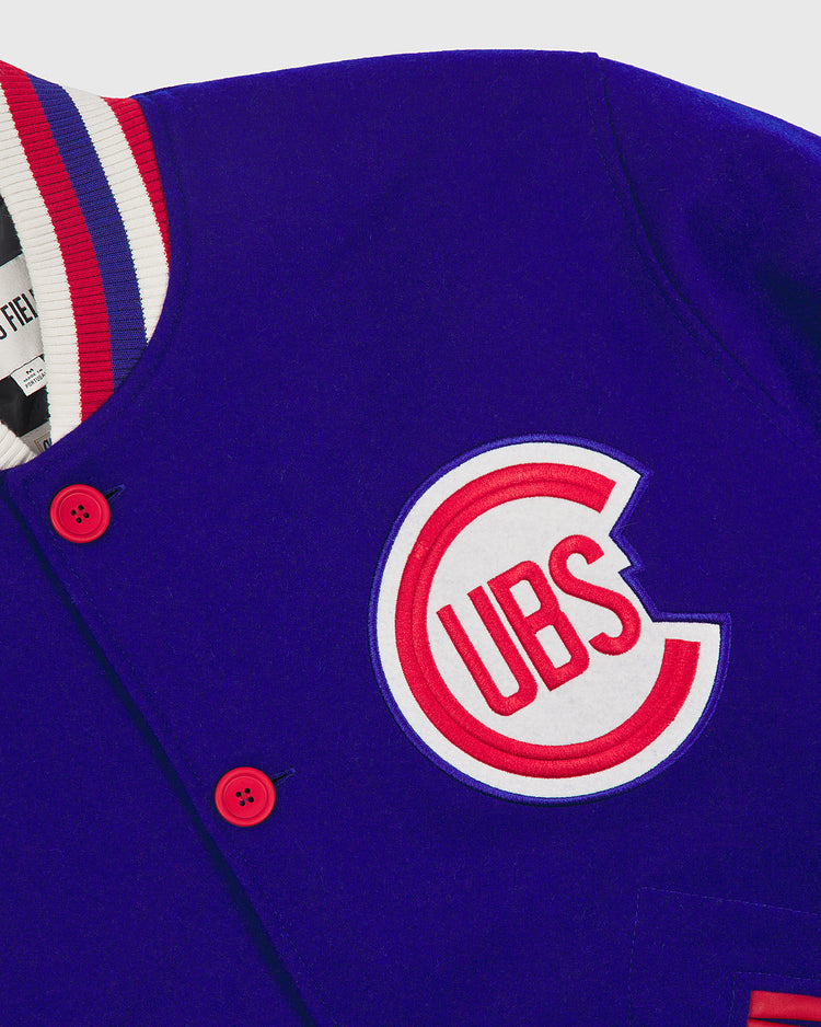A close-up of the EFF Chicago Cubs 1954 Authentic All Wool Varsity Jacket showcases its blue wool fabric, distinctive red buttons, and classic Cubs logo patch on the chest. The white collar features blue and red stripes, capturing the timeless style of a vintage varsity jacket.