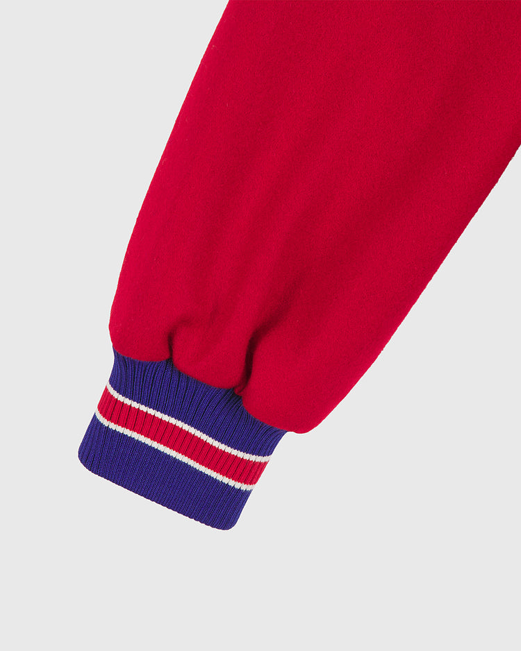 A close-up of the sleeve of the Philadelphia Phillies 1949 Authentic All Wool Varsity Jacket by EFF, featuring a red sleeve and a gathered blue cuff with two thin white stripes and one red stripe, set against a plain light background.