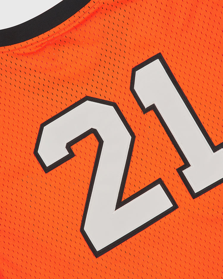 Close-up of The Clemente Museum x Ebbets Field V-Neck Mesh Jersey in vibrant orange mesh, featuring the number 21 in bold white with a black outline and tackle twill appliqué. The classic Ebbets Field mesh fabric and part of the black collar evoke the timeless style of a Roberto Clemente jersey.