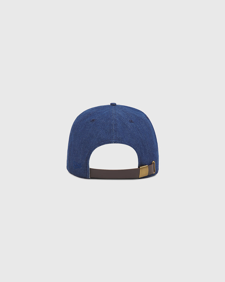 The Ebbets Field Hiroshima Carp Indigo Cotton Denim Twill Ballcap is displayed from the back, showcasing its brown adjustable strap with a metal buckle. The background is plain and light gray.