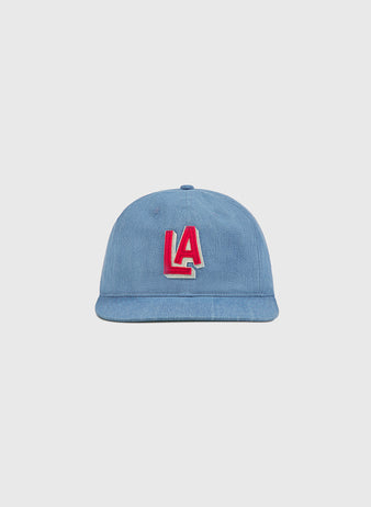 An indigo cotton denim ballcap by Ebbets Field, featuring a striking red and white LA logo on the front inspired by classic PCL history, is displayed against a plain light gray background.