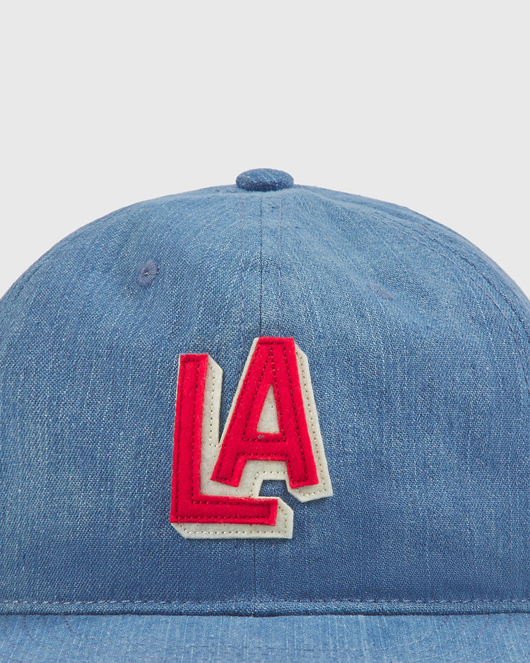 A close-up of the Ebbets Field Los Angeles (PCL) Indigo Cotton Denim Ballcap, featuring bold red and white LA embroidery on the front, inspired by classic Los Angeles Angels ballcap designs and celebrating PCL history.
