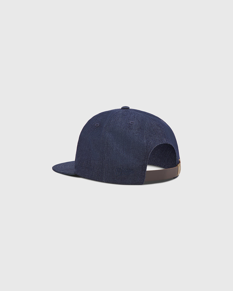 The Ebbets Field Brooklyn Bushwicks Indigo Cotton Denim Ballcap is displayed from the back and side, showcasing its curved brim and adjustable strap with a metal buckle. The background is plain light gray.