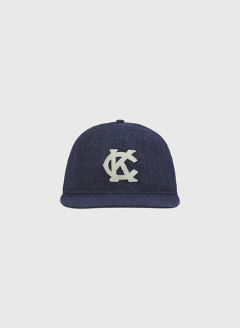 The Kansas City Monarchs Indigo Cotton Denim Ballcap by Ebbets Field features a flat brim and an interlocking KC logo embroidered in white on the front, embracing vintage sports style against a plain light gray background.