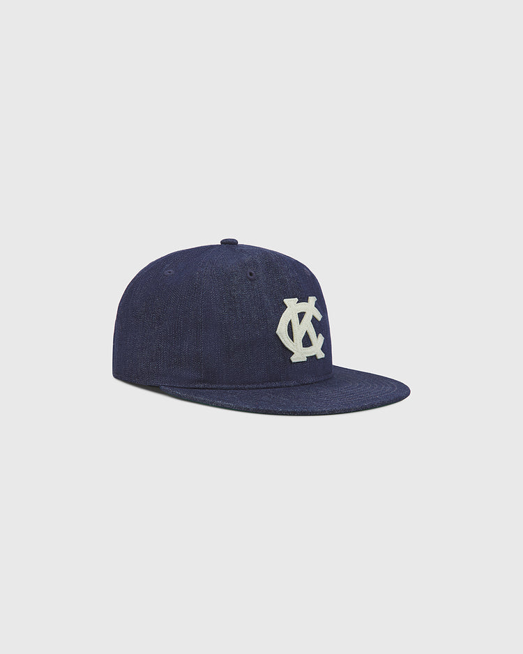 An indigo cotton denim ballcap by Ebbets Field, inspired by the Kansas City Monarchs, featuring a flat brim and a white interlocking 