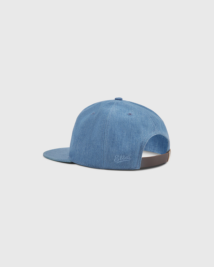 The Ebbets Field New York Brooklyn Eagles Indigo Cotton Denim Ballcap is a light blue denim cap with a flat brim, seen from the back. Drawing inspiration from the Brooklyn Eagles of the Negro Leagues, it features an adjustable strap and subtle embroidered text near the opening.