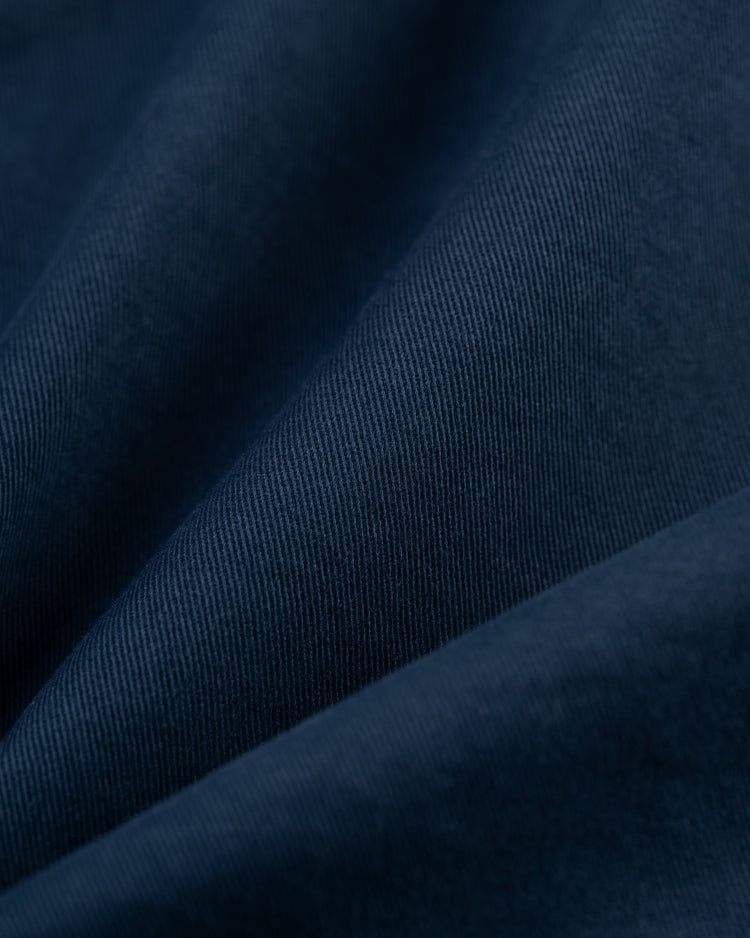 Close-up of deep blue cotton fabric from the Ebbets Field Cotton Grounds Crew Jacket by Ebbets Field Flannels, showing a soft, smooth texture with subtle diagonal folds that highlight the fine weave lines.