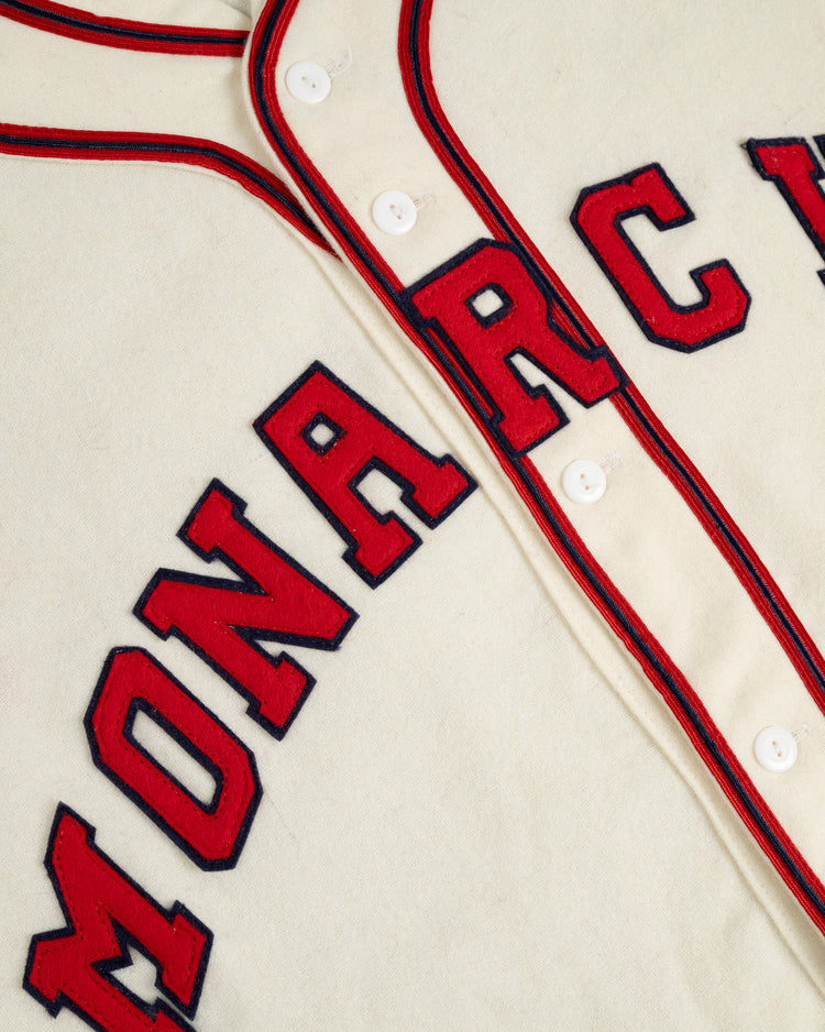 A close-up of the Ebbets Field Kansas City Monarchs 1942 Authentic Wool Home Baseball Jersey, cream-colored with red and black trim, white buttons, and bold MONARC letters across the front, inspired by the historic Negro Leagues team.
