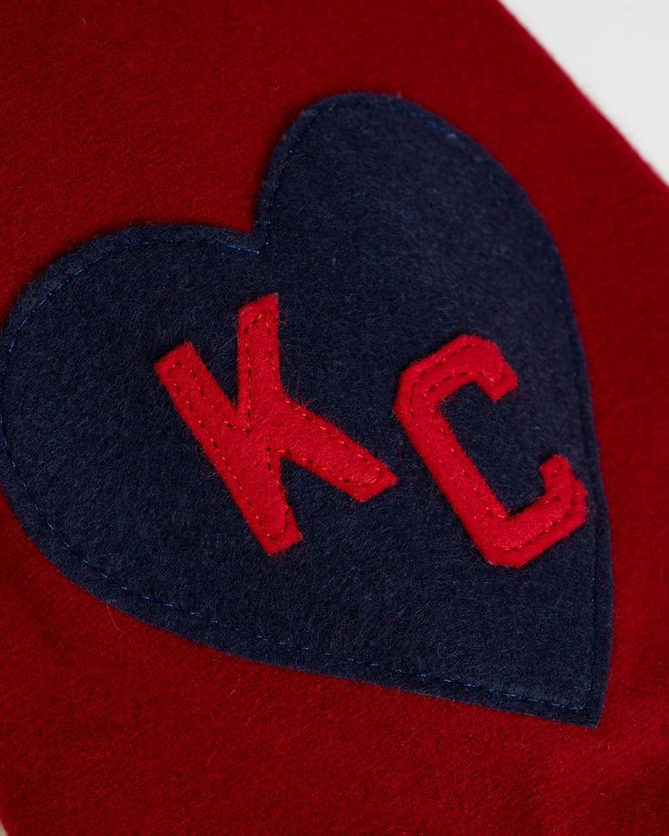 A navy blue heart-shaped patch with red stitched KC, inspired by the Kansas City Monarchs, is sewn onto the Ebbets Field Kansas City Monarchs 1942 Authentic Wool Home Baseball Jersey.