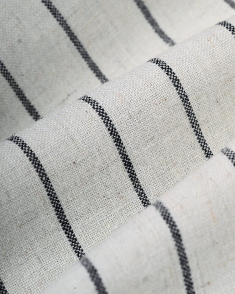 A close-up of the Ebbets Field Flannels Homestead Grays 1944 Authentic Wool Home Baseball Jersey shows off-white wool fabric with thin black stripes, folded to create soft lines and shadows, evoking the classic jersey design.