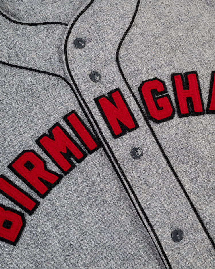 Close-up of the Birmingham Black Barons 1948 Authentic Wool Road Baseball Jersey by Ebbets Field, featuring bold red and black “BIRMINGHAM” lettering and black piping, honoring the legacy of the Negro Leagues Baseball Museum.