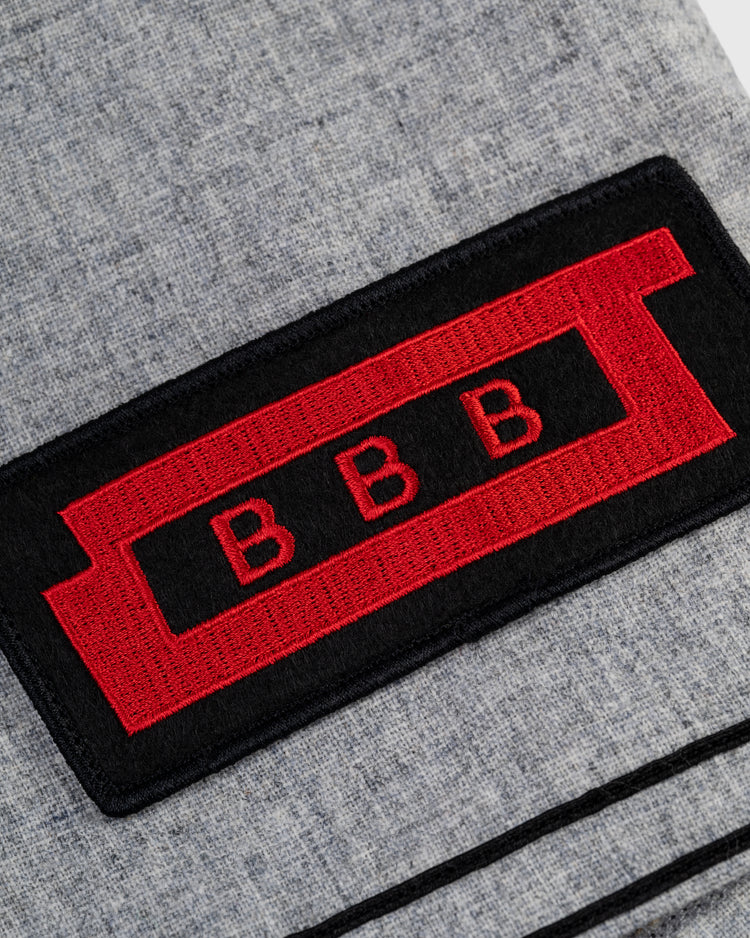 A black and red rectangular BBB patch, sewn onto textured grey wool, recalls the iconic style of the Birmingham Black Barons 1948 Authentic Road Baseball Jersey by Ebbets Field, as seen at the Negro Leagues Baseball Museum.